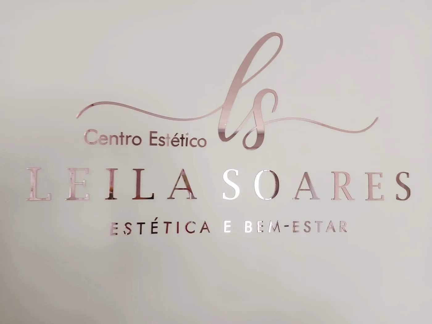 Parede clara com o logo Centro Estético Leila Soares em letras de acrílico rosé